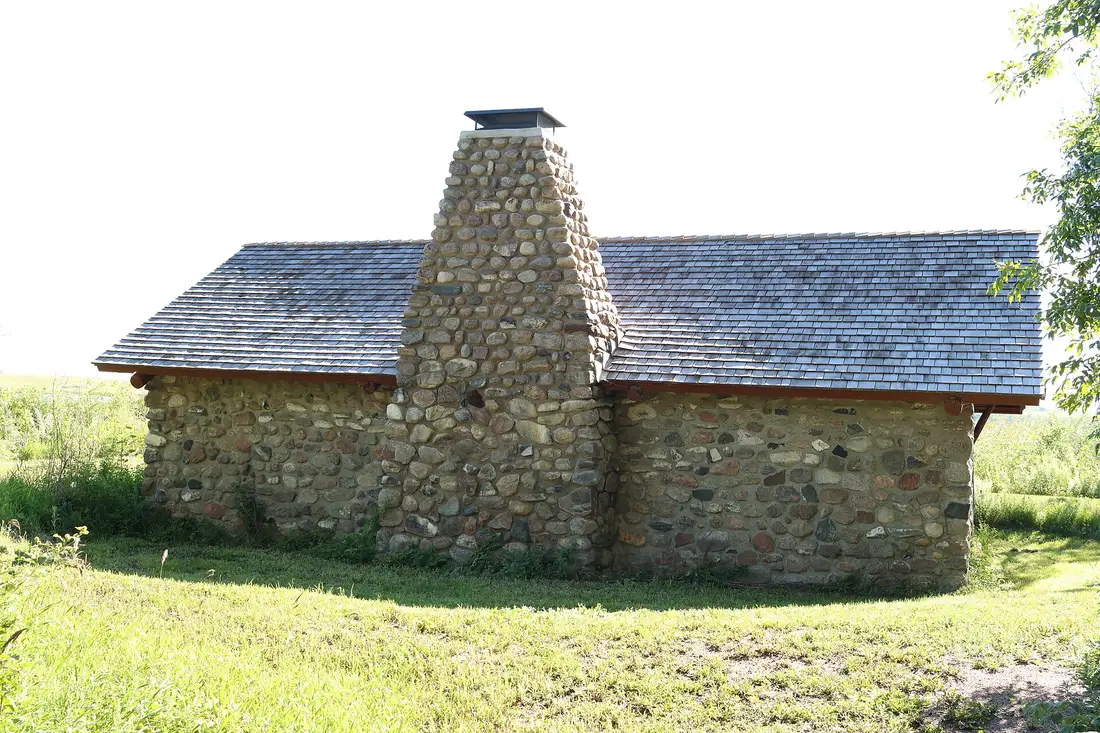 New cedar shingle roof on a fieldstone building with a tall stone chimney